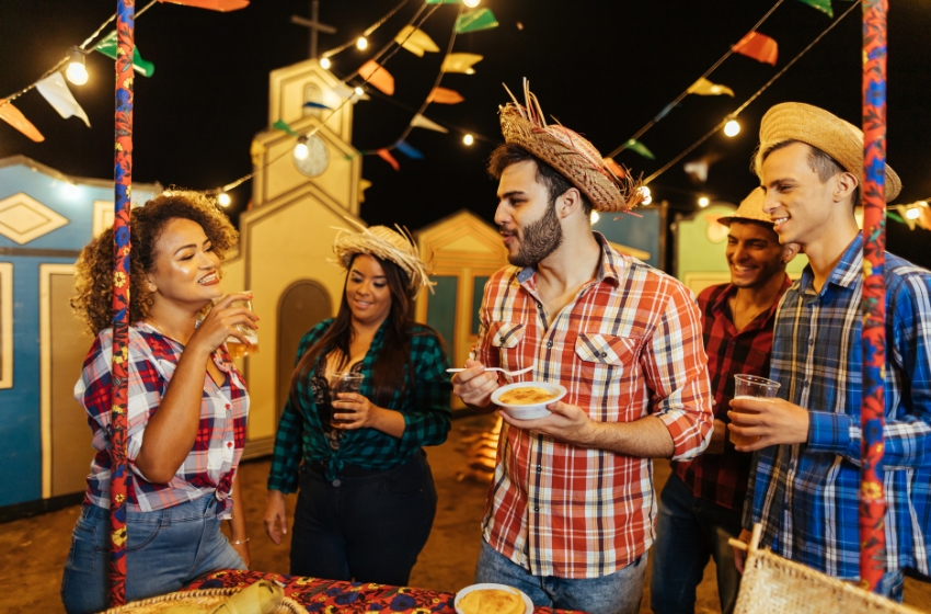 homens e mulheres em festa junina usando roupas a carater e comendo comida típicas