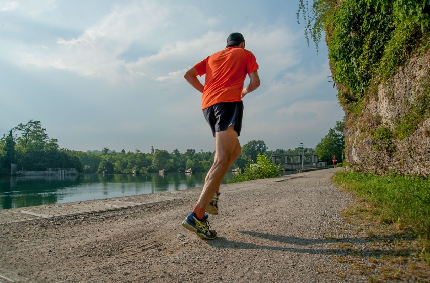 homem usando roupas e tênis esportivos correndo em uma trilha