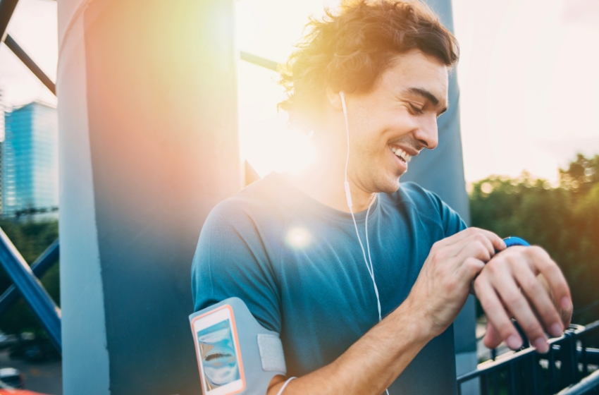 homem sorrindo e vendo relógio na caminhada