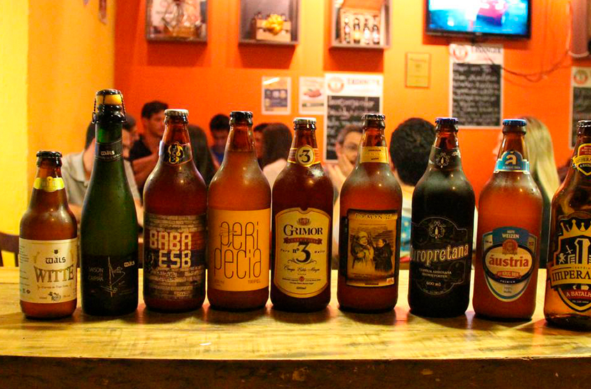 garrafas de cerveja dispostas sobre o balcão de um bar