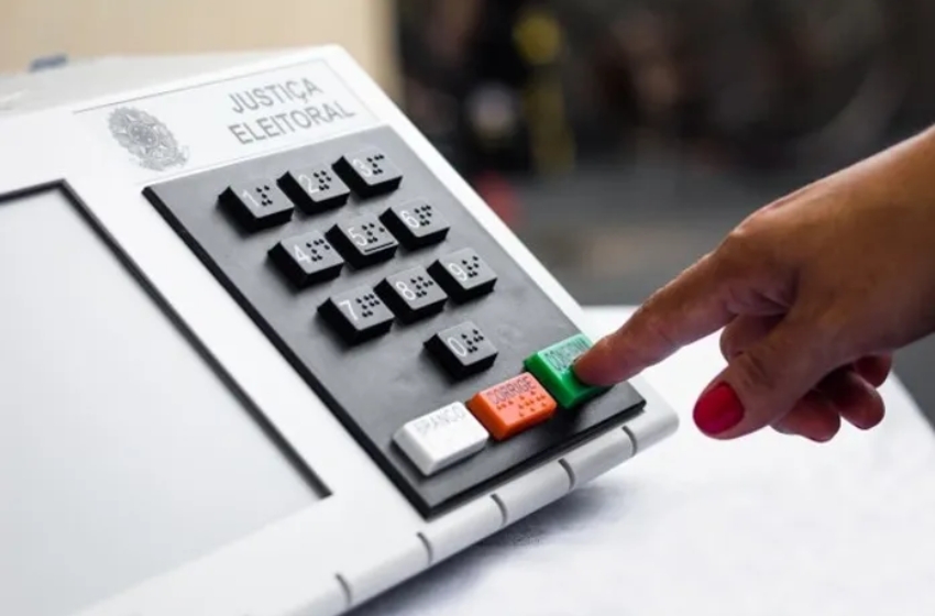 Botão verde da urna eletrônica sendo pressionado
