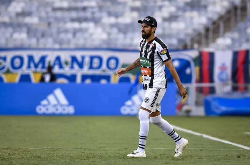Loco Abreu, um atacante moreno, veste a camisa listrada de preto e branco do Athletic. Ele também está com um calção branco, além de meias e chuteiras brancas. Em seu fundo está uma bandeira branca, com a escrita Comando Rasta em letras azuis.