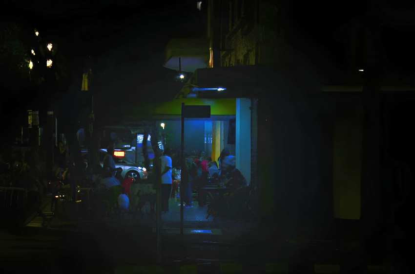A imagem mostra um bar de BH ao anoitecer, com muitos clientes ainda no local. O local se localiza próximo a praça Raul Soares.